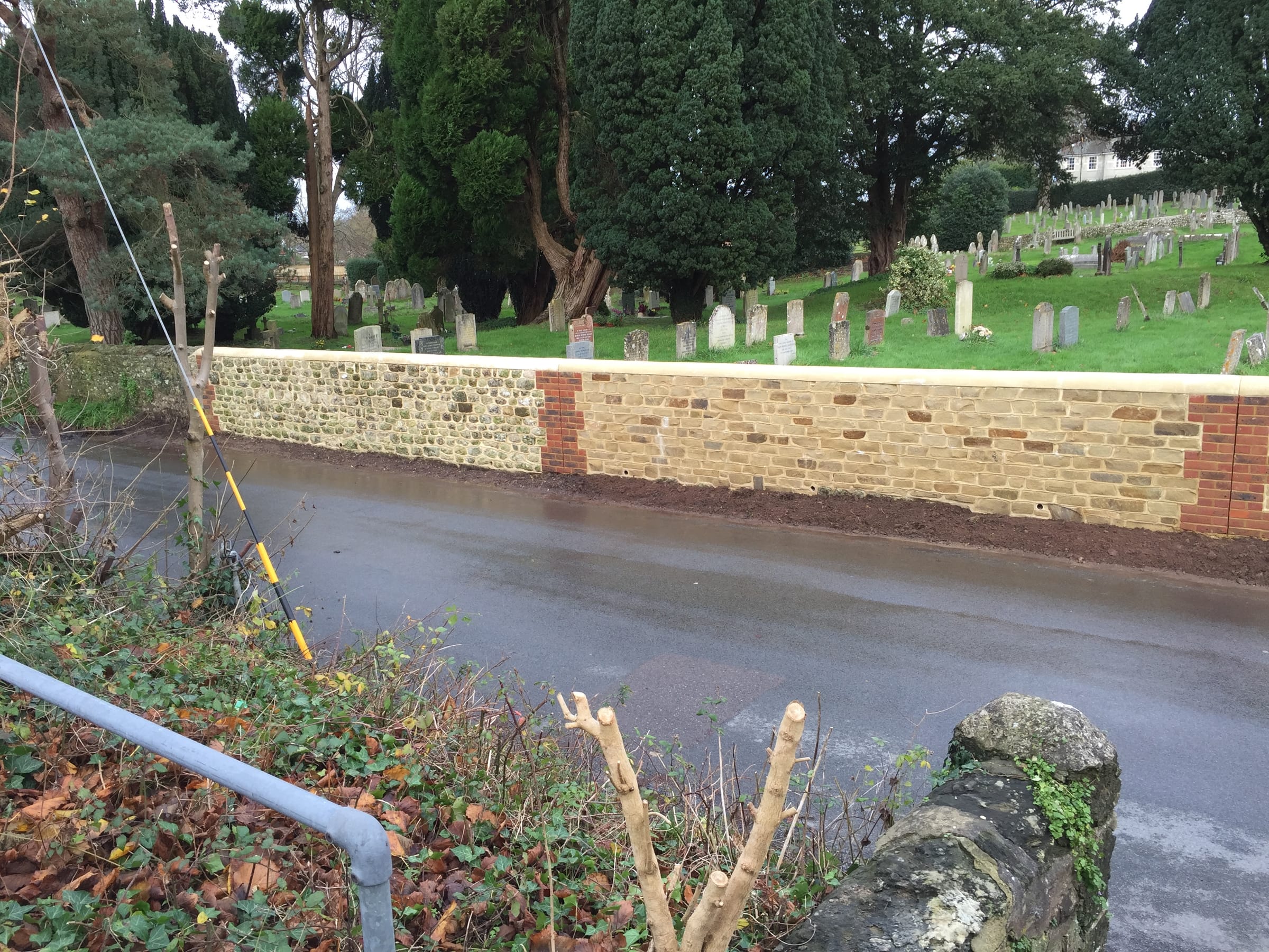 Flint and brick boundary wall along a lane