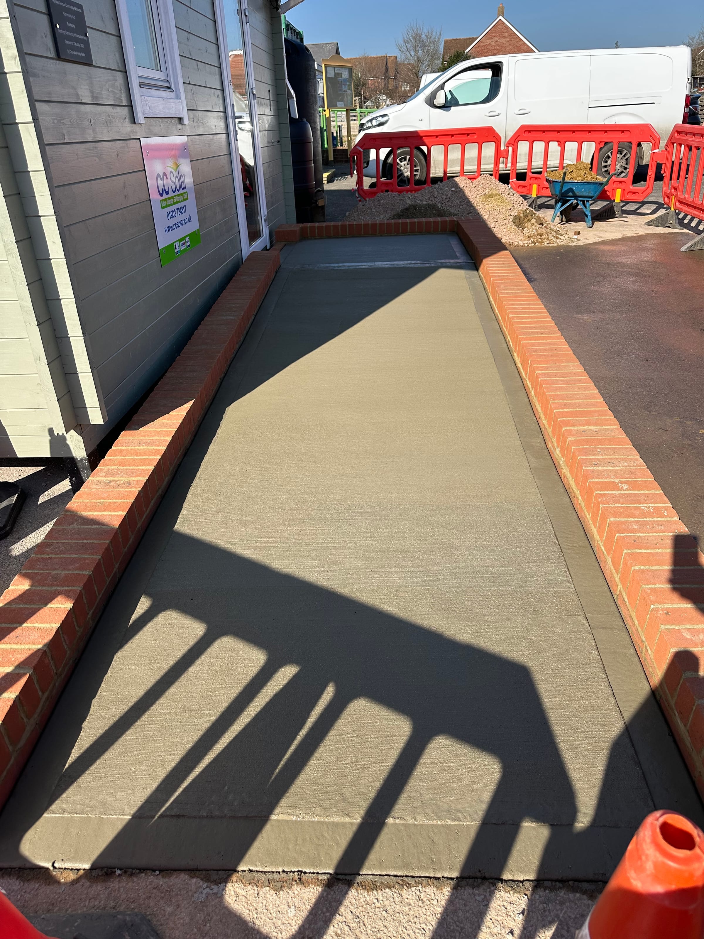 Brick-edged concrete access ramp to a garden cabin