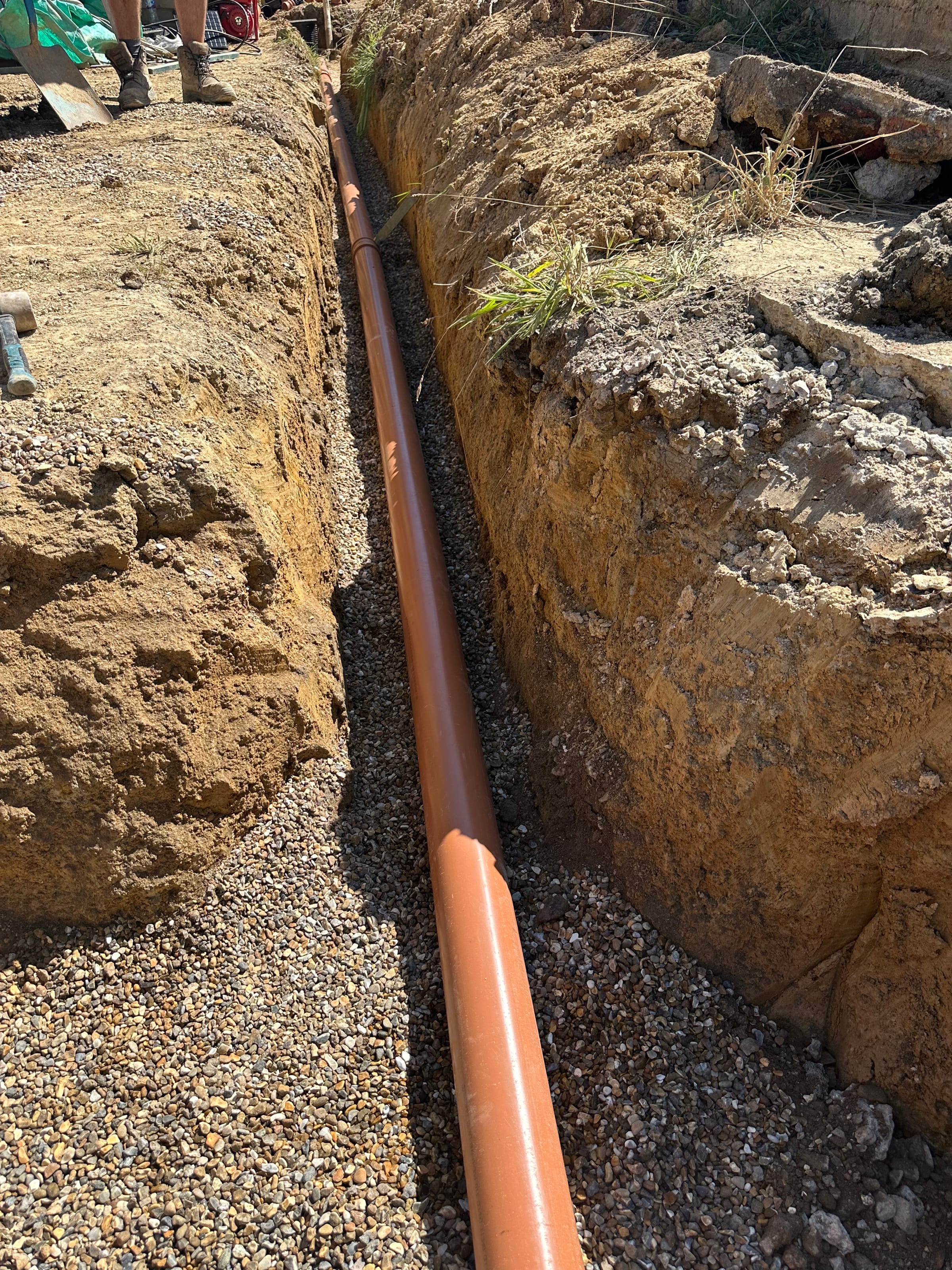New drainage pipe run laid in a gravel-backed trench