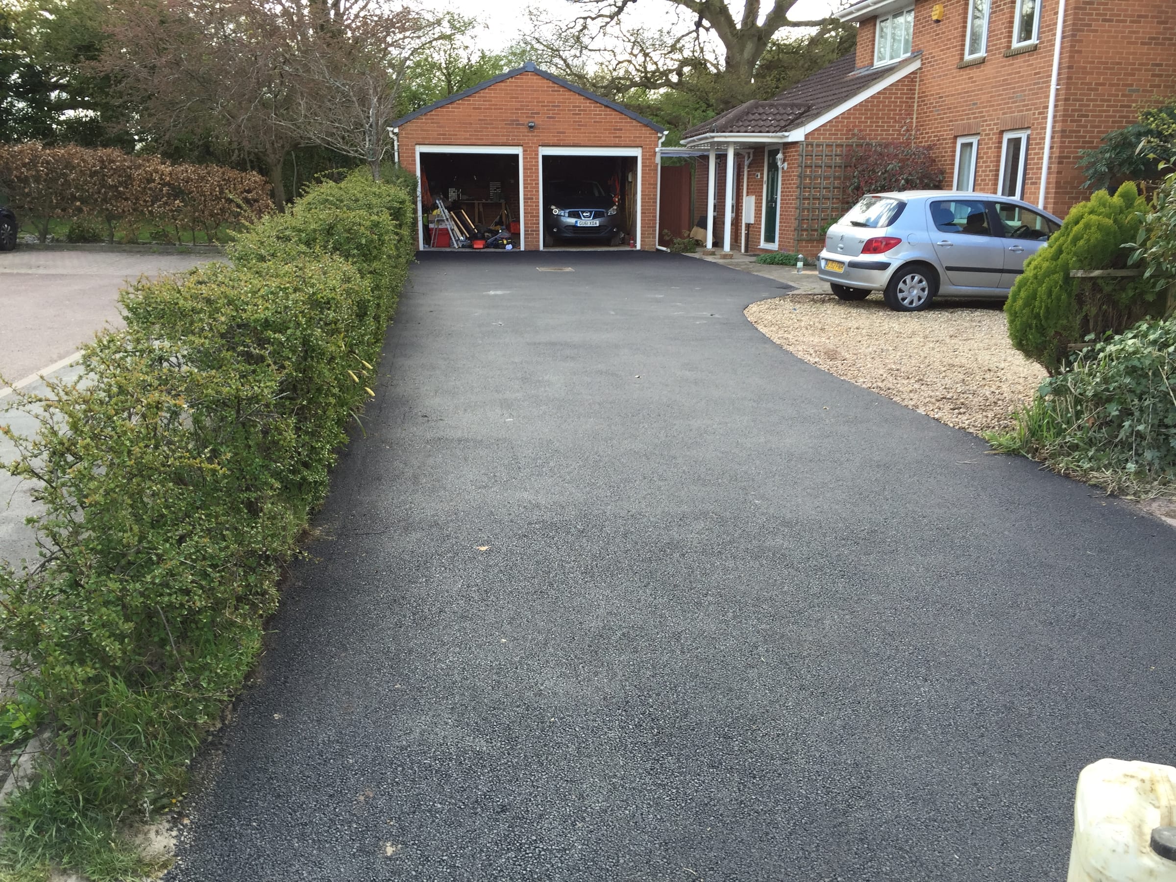 Resurfaced tarmac driveway leading to a double garage
