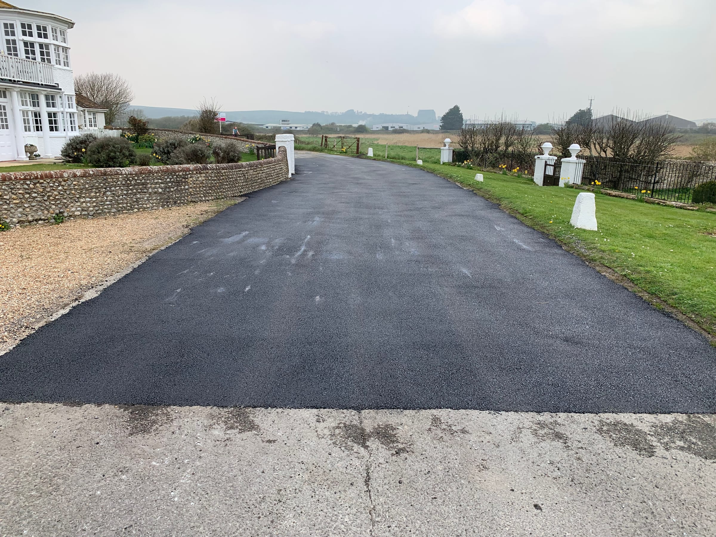 Sweeping tarmac driveway with stone entrance pillars