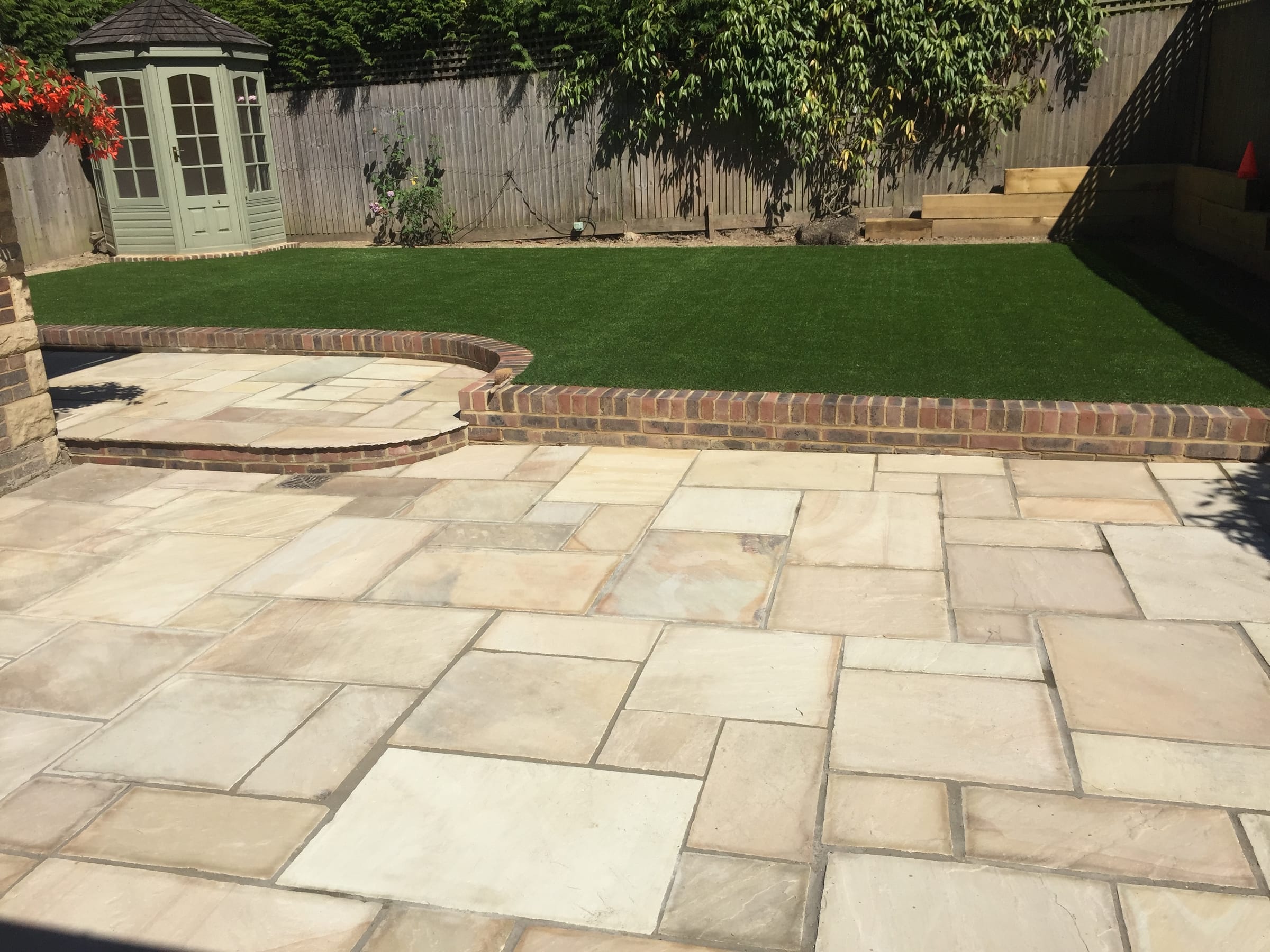 Indian stone patio with artificial lawn and brick edging